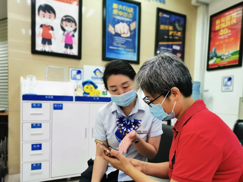 建行成都第六支行，大堂經理為客戶介紹手機銀行&ldquo;大字&rdquo;模式